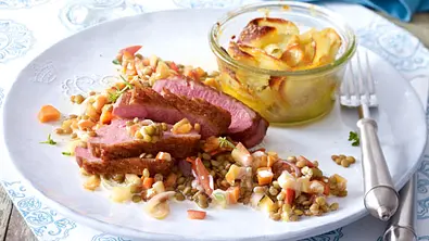 Entenbrust auf Calvados-Linsen mit Kartoffelgratin auf einem weißen Teller angerichtet. - Foto: LECKER @ Bauer Media Group