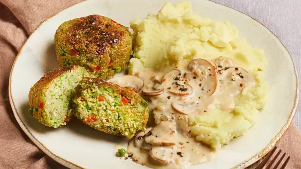 Erbsenfrikadellen auf einem Teller mit Kartoffelpüree und Pilzsoße serviert. - Foto: StockFood Studios/Meike Bergmann
