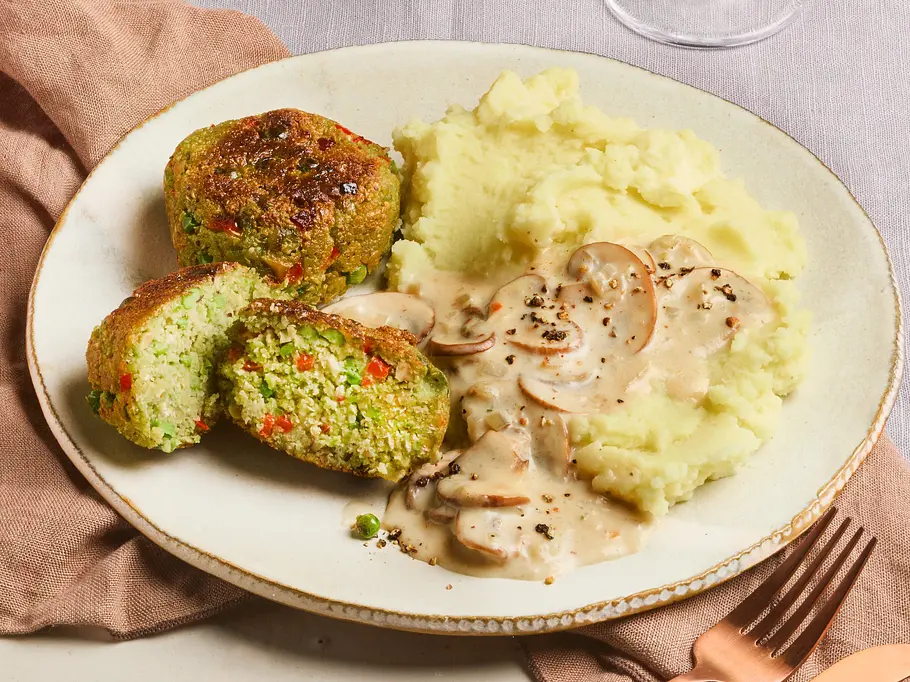 Erbsenfrikadellen auf einem Teller mit Kartoffelpüree und Pilzsoße serviert.