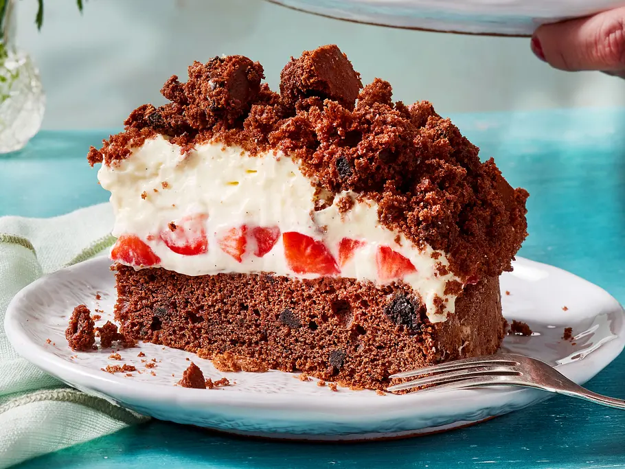 Erdbeer-Maulwurfkuchen mit Oreos Eine großes Kuchenstück mit Schokoboden, Erdbeeren und Sahnecreme liegt auf einem weißen Teller.