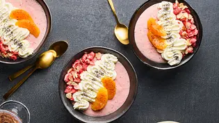 Vier Schüsseln mit cremigem, rosa Erdbeer-Pudding, getoppt mit Blutorangenfilets, Joghurtcreme, gehackten Nüssen und gefriergetrockneten Erdbeerstückchen, serviert auf einem dunklen Untergrund. Daneben ein Teller mit Blutorangenscheiben und Nüssen. - Foto: LECKER @ Bauer Media Group