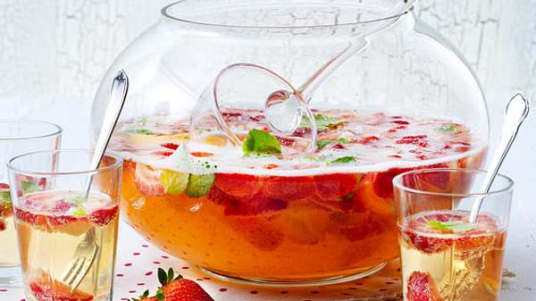 Erdbeerbowle in einem Bowle-Gefäß mit Schöpflöffel, daneben 3 Gläser mit Bowle und kleinen Gabeln - Foto: House of Food / Bauer Food Experts KG