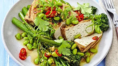 Gegrillte Tofuscheiben auf einem Bett aus grünem Gemüse wie Brokkolini, Edamame und grünen Bohnen, garniert mit frischen Kräutern und Chiliringe. - Foto: LECKER @ Bauer Media Group