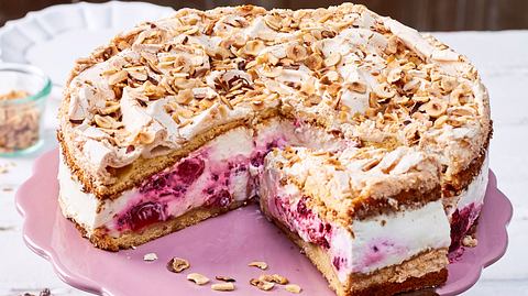 Baiser-Torte mit knusprigen, weißen Baiserböden, cremiger Füllung und bunten, in Rum getränkten Trockenfrüchten, auf einer Tortenplatte serviert. - Foto: LECKER @ Bauer Media Group