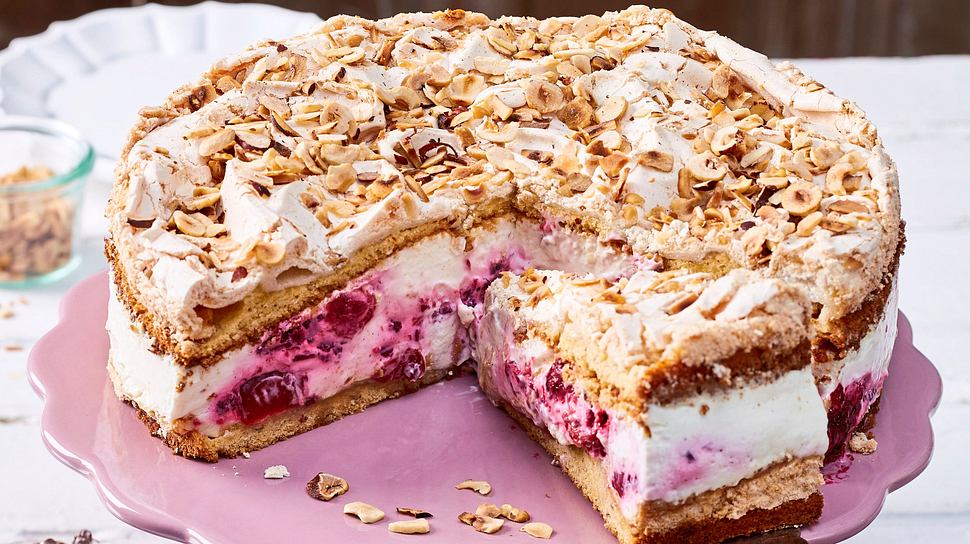 Baiser-Torte mit knusprigen, weißen Baiserböden, cremiger Füllung und bunten, in Rum getränkten Trockenfrüchten, auf einer Tortenplatte serviert. - Foto: LECKER @ Bauer Media Group