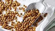 Knusprig geröstete Kichererbsen auf einem mit Backpapier belegten Blech, serviert mit Gewürzen. Im Vordergrund eine kleine Schale mit gerösteten Kichererbsen. - Foto: LECKER @ Bauer Media Group Knusprig geröstete Kichererbsen auf einem mit Backpapier belegten Blech, serviert mit Gewürzen. Im Vordergrund eine kleine Schale mit gerösteten Kichererbsen. - Foto: LECKER @ Bauer Media Group
