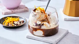 Affogato mit Vanilleeis, Espresso, Orangenzesten und gehackten Nüssen in einem niedrigen Glas auf weißem Untersetzer serviert. - Foto: LECKER @ Bauer Media Group