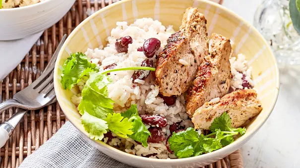Aromatischer Kokosreis mit roten Bohnen und frischem Koriander, serviert mit saftigen, gebratenen Pfeffer-Putenstreifen in einer gelben Schale. - Foto: LECKER @ Bauer Media Group