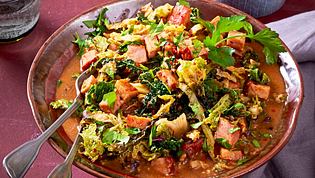 Würziges Ragout mit Kasselerwürfeln, Wirsing, asiatischen Gewürzen und frischen Kräutern, serviert in einer braunen Schale. - Foto: LECKER @ Bauer Media Group