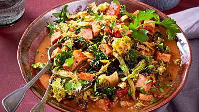 Würziges Ragout mit Kasselerwürfeln, Wirsing, asiatischen Gewürzen und frischen Kräutern, serviert in einer braunen Schale. - Foto: LECKER @ Bauer Media Group