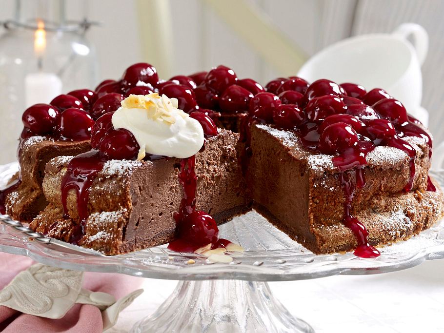 Schokoladen-Käsekuchen mit cremiger Konsistenz, üppig belegt mit Kirschkompott und einem Klecks Sahne.