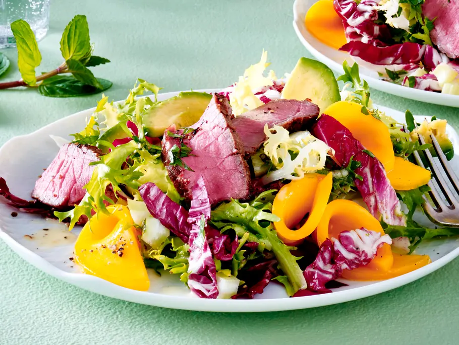 Avocado-Mango-Salat mit Steakstreifen auf einem Teller Avocado-Mango-Salat mit Steakstreifen auf einem Teller
