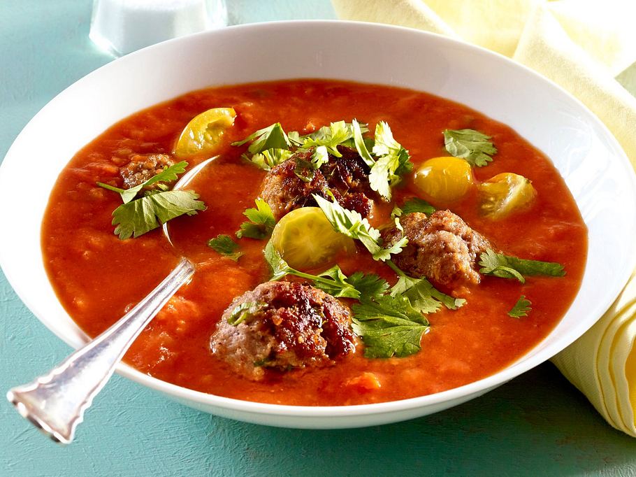 Cremige Tomaten-Kokos-Suppe mit saftigen Rinderbällchen, gelben Tomaten und frischem Koriander.