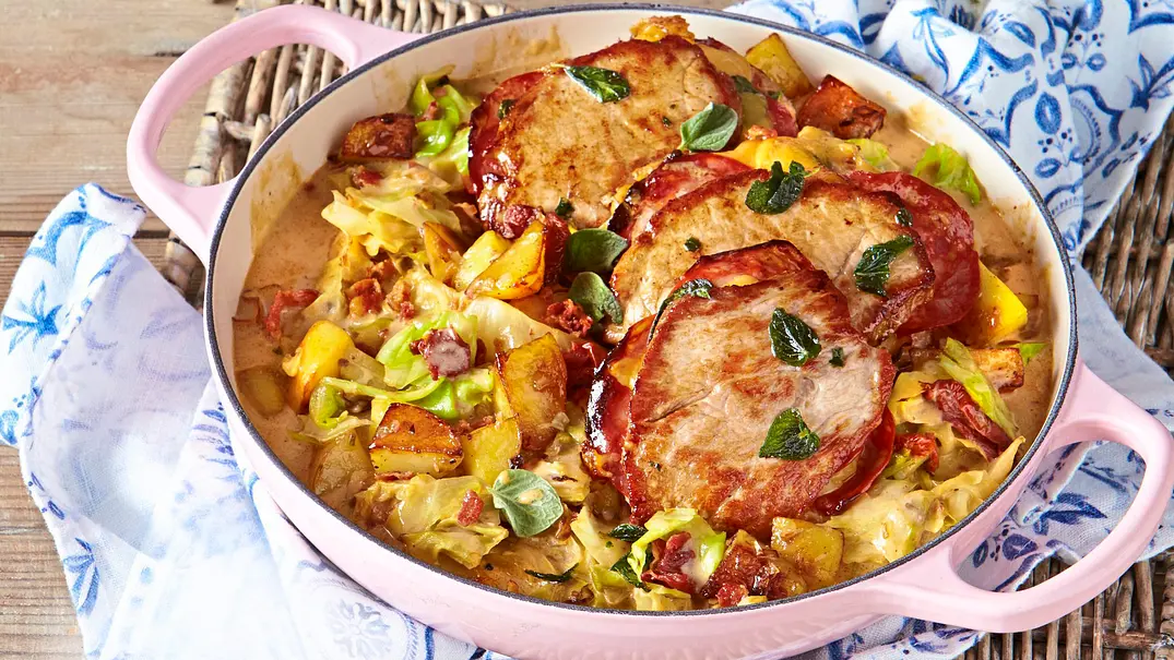 Mit Schinken umwickelte, gefüllte Schnitzel auf einer Pfanne mit gebratenem Spitzkohl, Kartoffelstücken und Kräutern, serviert in einer rosafarbenen Auflaufform. - Foto: LECKER @ Bauer Media Group