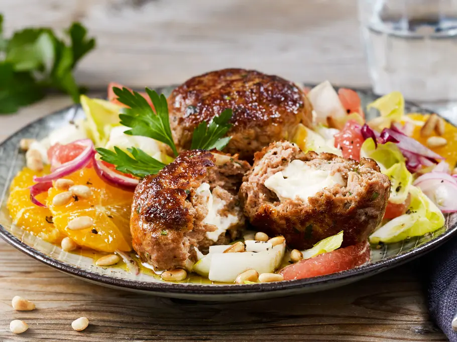Feta-Frikadellen mit Chicorée-Zitrus-Salat auf einem Teller angerichtet