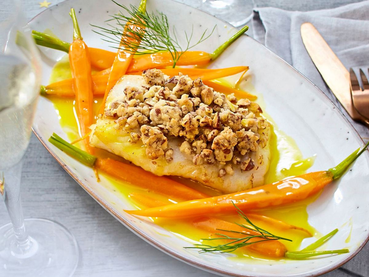 Seelachsfilet mit knuspriger Mandelkruste, serviert auf einem Teller und mit frischen Kräutern garniert.