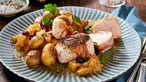 Zarte Puten-Medaillons, umwickelt mit Speck und Lorbeer, serviert mit kleinen Kartoffeln und fruchtigem Apfel-Kompott auf einem grünlich-blauen Keramikteller. - Foto: LECKER @ Bauer Media Group