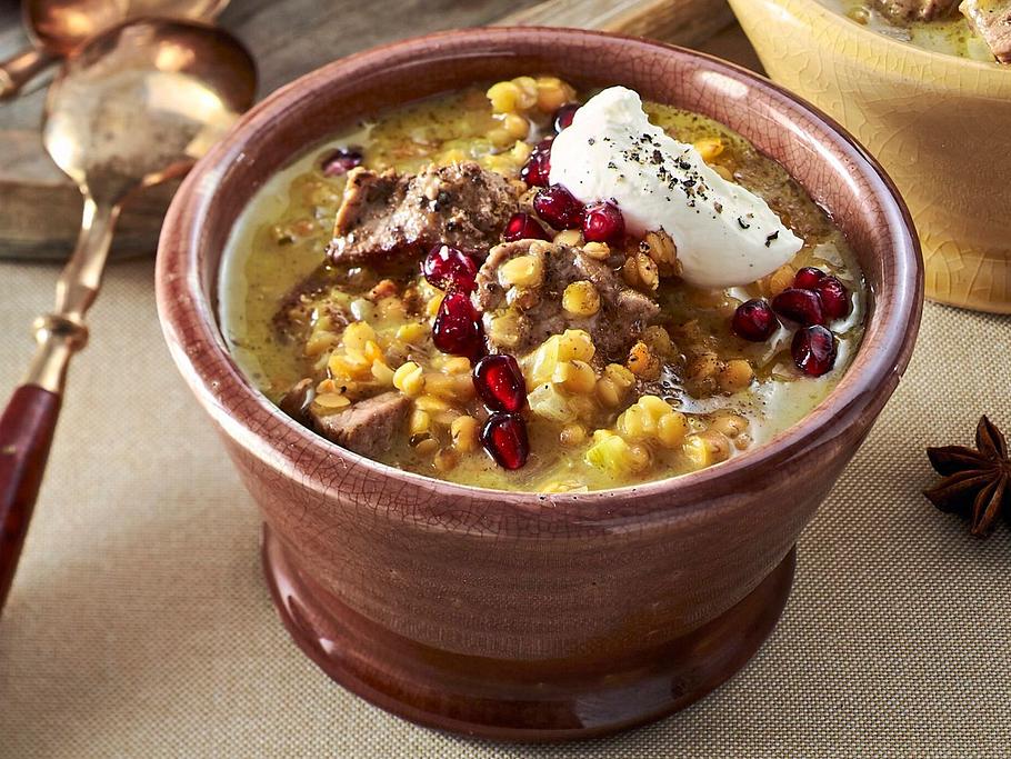 Cremiges Linsen-Dal mit zarten Stücken Schweinefilet, serviert mit Joghurt und Granatapfelkernen als Topping.