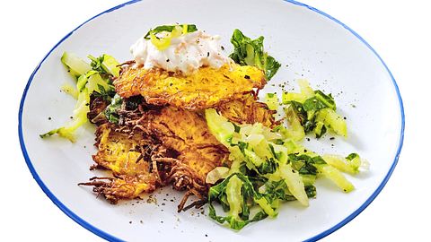Knusprige Karotten-Kartoffel-Puffer mit cremigem Dip und Mangoldgemüse auf einem weißen Teller angerichtet. - Foto: LECKER @ Bauer Media Group