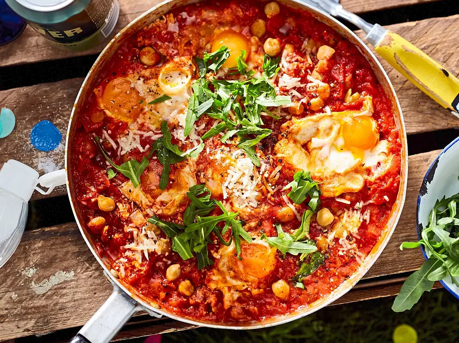 Pfanne mit Tomatensoße, Kichererbsen, Eiern und Rukola.