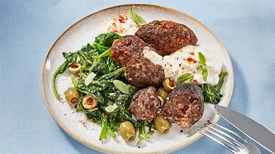 Paprika-Cevapcici zu Spinat mit Oliven und Mozzarella auf einem Teller angerichtet aus dem Airfryer - Foto: LECKER @ Bauer Media Group