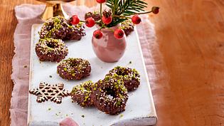 Schokokringel aus Schokoladenteig, in Ringform gebacken, mit gehackten Pistazien und bunten Zuckerstreuseln bestreut und auf einem weißen Brett angerichtet. - Foto: LECKER @ Bauer Media Group