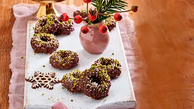Schokokringel aus Schokoladenteig, in Ringform gebacken, mit gehackten Pistazien und bunten Zuckerstreuseln bestreut und auf einem weißen Brett angerichtet. - Foto: LECKER @ Bauer Media Group