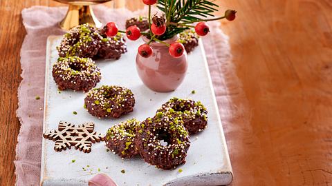 Schokokringel aus Schokoladenteig, in Ringform gebacken, mit gehackten Pistazien und bunten Zuckerstreuseln bestreut und auf einem weißen Brett angerichtet. - Foto: LECKER @ Bauer Media Group