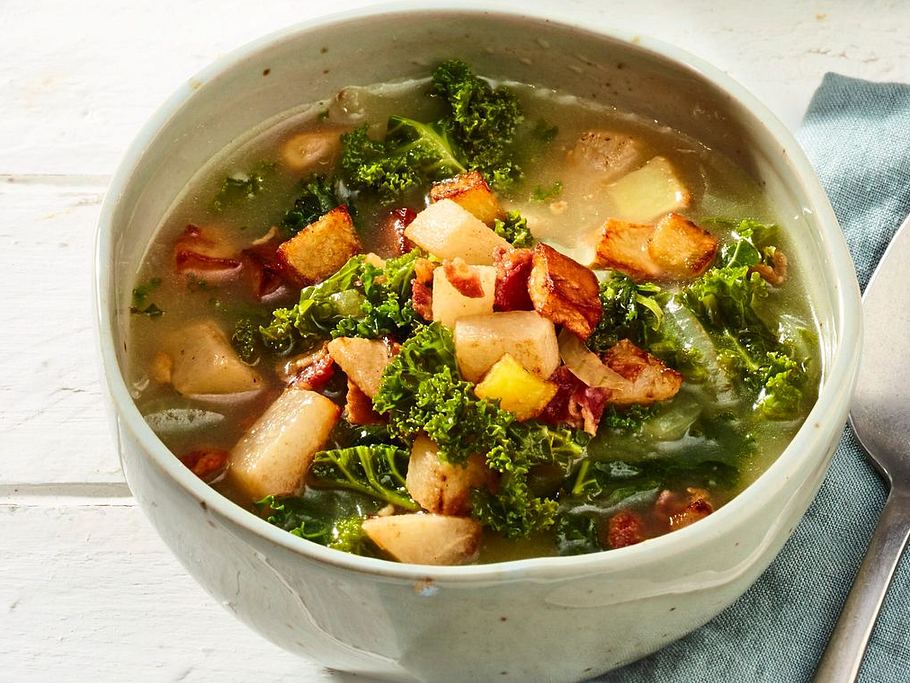 Kräftige Grünkohlsuppe in einer Keramikschale, serviert mit knusprigem Birnen-Speck-Topping.