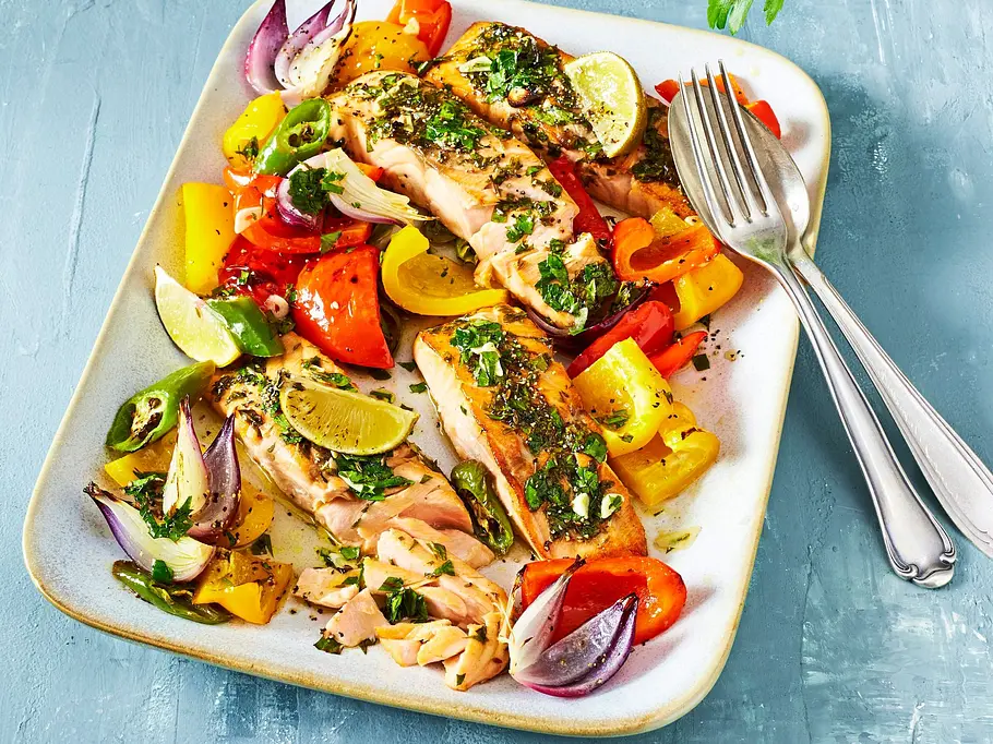 Kräuter-Lachs aus dem Airfryer Rezept Ein eckiger Teller mit Paprika, Zwiebeln, Limetten und Kräuter-Lachs.