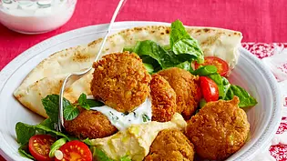 Selbstgemachte Falafelbällchen mit Salat, Tomaten, Dressing und einem Fladenbrot auf einem tiefen Teller serviert. - Foto: LECKER @ Bauer Media Group Selbstgemachte Falafelbällchen mit Salat, Tomaten, Dressing und einem Fladenbrot auf einem tiefen Teller serviert. - Foto: LECKER @ Bauer Media Group