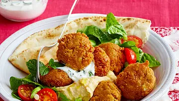 Selbstgemachte Falafelbällchen mit Salat, Tomaten, Dressing und einem Fladenbrot auf einem tiefen Teller serviert. - Foto: LECKER @ Bauer Media Group Selbstgemachte Falafelbällchen mit Salat, Tomaten, Dressing und einem Fladenbrot auf einem tiefen Teller serviert. - Foto: LECKER @ Bauer Media Group