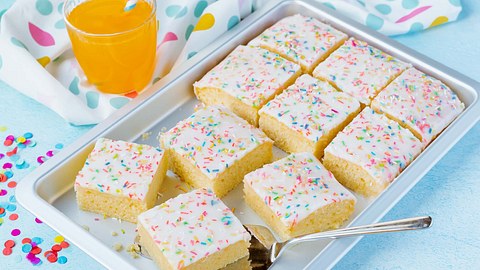 Bunter Fantakuchen - quadratisch geschnitten in einer Backform mit Tortenheber - Foto: ShowHeroes