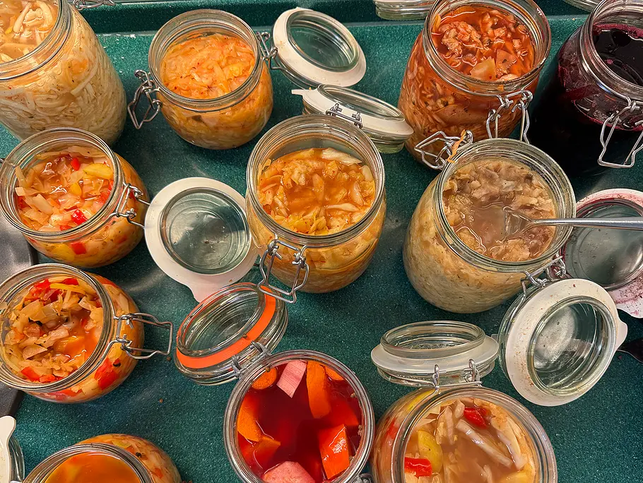 Auf einem Tisch mit grüner Oberfläche stehen verschiedene geöffnete Bügelgläser mit Fermenten