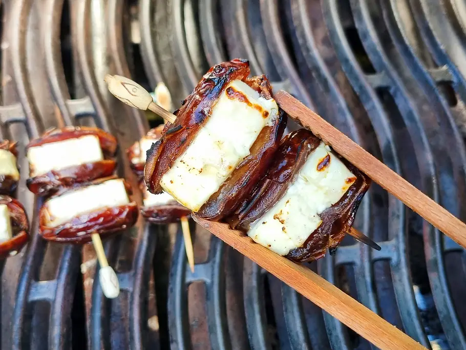 Feta-Dattel-Spieße grillen Gegrillte Dattel-Feta-Spieße werden vom Grill genommen.