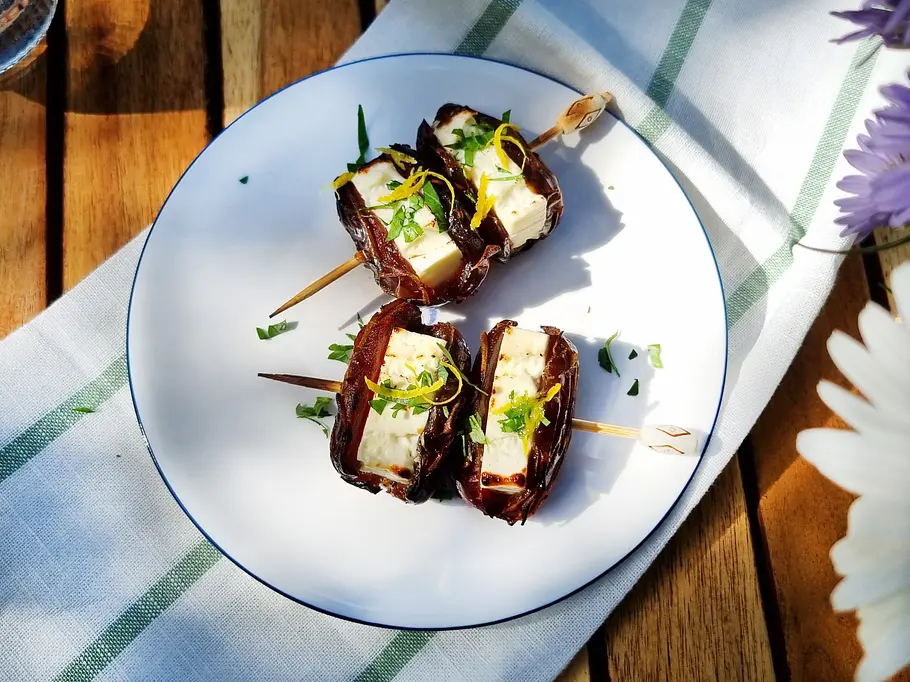 Feta-Datteln vom Grill Datteln mit Feta com Grill, aufgespießt und mit Zitronenzesten und Petersilie angerichtet.