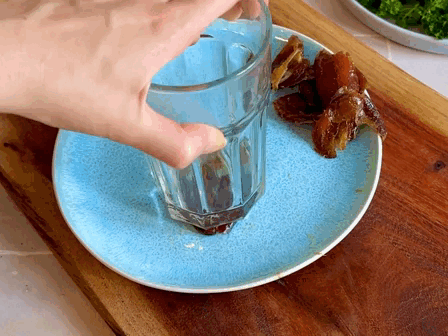 Feta-Stulle mit karamellisierten Datteln Rezept Ein Teller mit Datteln und ein Glas, mit dem eine Dattel zerdrückt wird.