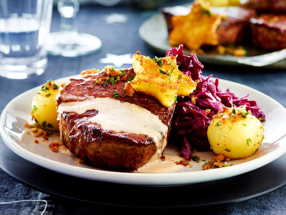 Filetsteak auf Teller mit Soße angerichtet. Dazu Knödel und Rotkohl