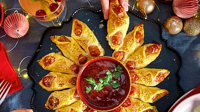 Fingerfood zu Weihnachten: Ein Kranz aus Würstchen im Schlafrock ist sternförmig um ein Dipschälchen arrangiert. - Foto: LECKER @ Bauer Media Group