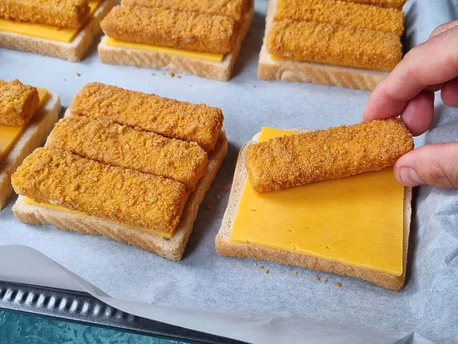 Fischstäbchen-Toasts zubereiten Fischstäbchen werden auf die mit Käse belegten Toastscheiben verteilt.