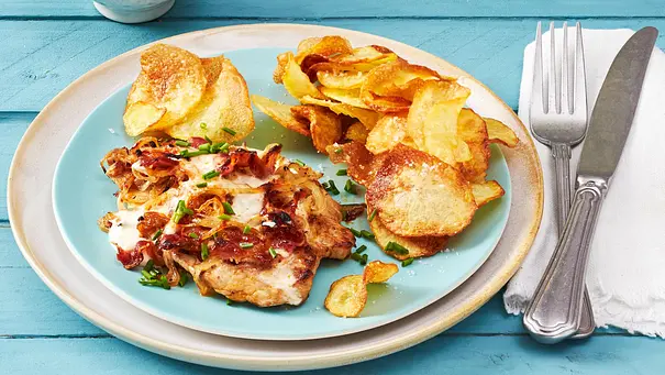 Flammkuchen Schnitzel aus dem Airfryer auf einem hellblauen Teller. Daneben eine weiße Serviette, auf der Besteck liegt. - Foto: LECKER @ Bauer Media Group