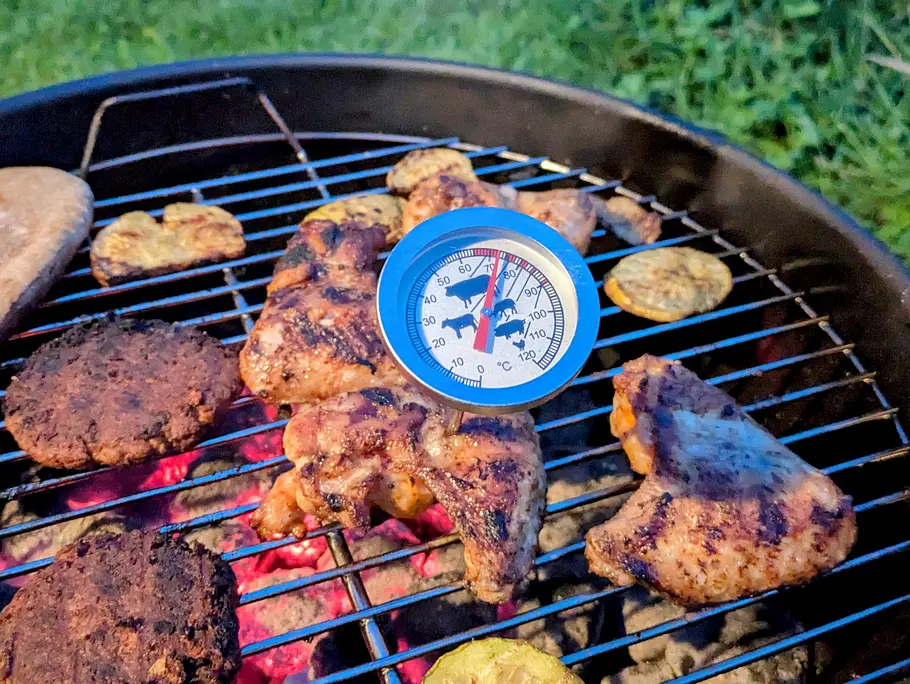 Analoges Fleischthermometer Hähnchenschenkel Analoges Fleischthermometer in einem Hähnchenschenkel auf einem Weber Kugelgrill.