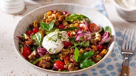 Bunt gemischte Bowl mit Hackfleisch, roten Johannisbeeren, Babyleafsalat und einen Klecks Schmand on top in einer weißen Schüssel auf hellem Untergrund. - Foto: House of Food / Bauer Food Experts KG 