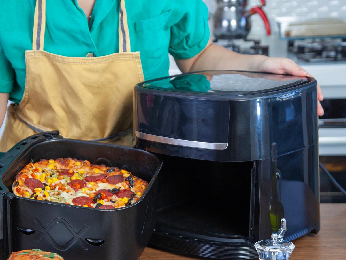 Frau kocht Pizza in der Heißluftfritteuse
