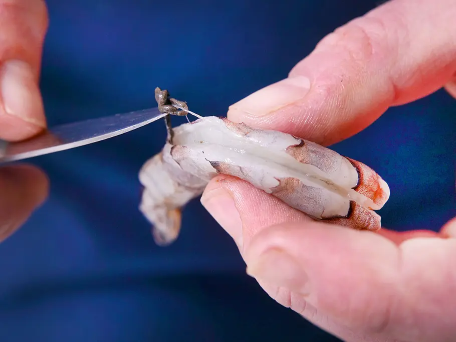 Garnele, die mit Hilfe eines spitzen Küchenmessers entdarmt wird.