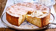 Gedeckter Apfelkuchen aus der Springform mit Zuckerguss, ein Stück herausgeschnitten und mit einem Klecks Sahne bestreut serviert. - Foto: LECKER @ Bauer Media Group