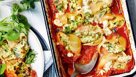 Gefüllte Muschelnudeln mit Tomatensoße in der Auflaufform mit Servierlöffel und ein angerichteter Teller mit grünem Salat  - Foto: House of Food / Bauer Food Experts KG