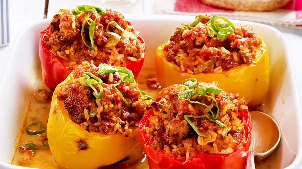 Mit Hackfleisch gefüllte rote und gelbe Paprikas in einer weißen Auflaufform. - Foto: ShowHeroes für LECKER @ Bauer Media Group Mit Hackfleisch gefüllte rote und gelbe Paprikas in einer weißen Auflaufform. - Foto: ShowHeroes für LECKER @ Bauer Media Group