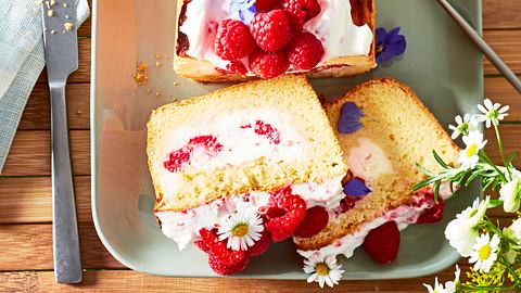 Gefüllter Cheesecake-Kastenkuchen mit Himbeeren und Blüten auf Servierteller mit Kuchengabeln - Foto: House of Food / Bauer Food Experts KG