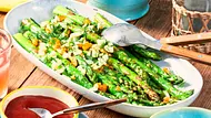 Gegrillter grüner Spargel auf einer ovalen Platte mit angelegtem Servierbesteck - Foto: LECKER @ Bauer Media Group